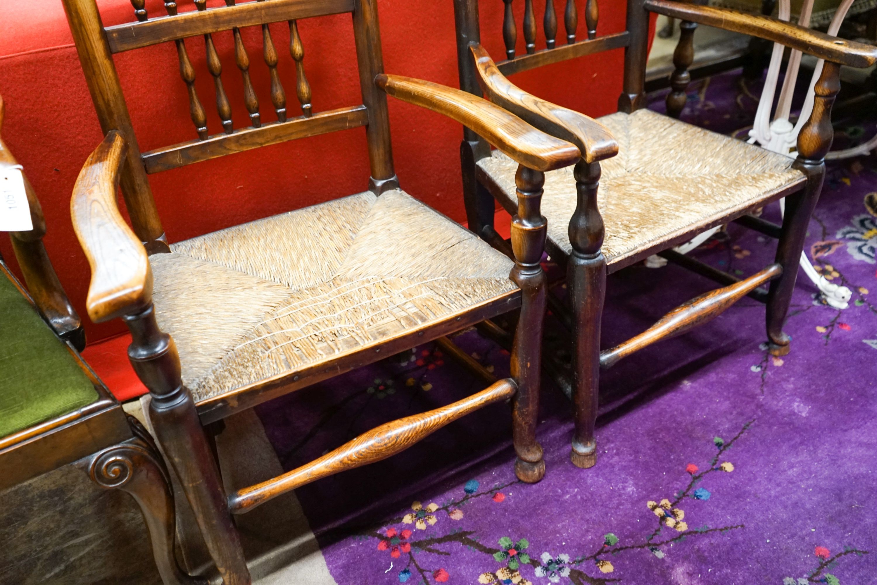 A near pair of Lancashire ash and elm rush seat spindle back elbow chairs